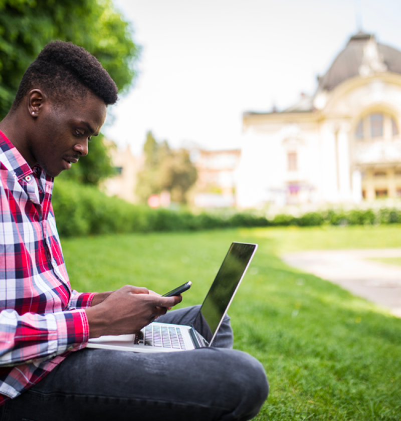 young-attractive-afro-american-businessman-with-laptop-sitting-grass-talking-cell-phone-park